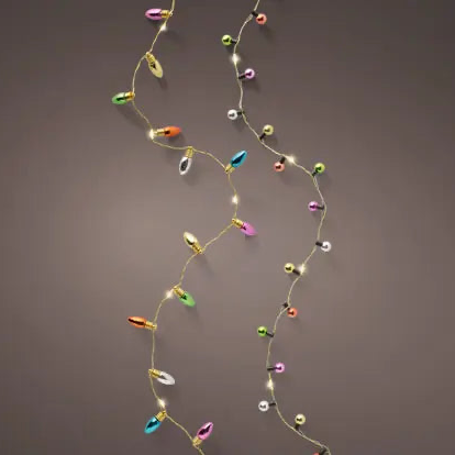 Multicolor Christmas string lights with glowing warm white bulbs and colorful reflective ornaments, arranged in two vertical strands against a dark brown background.