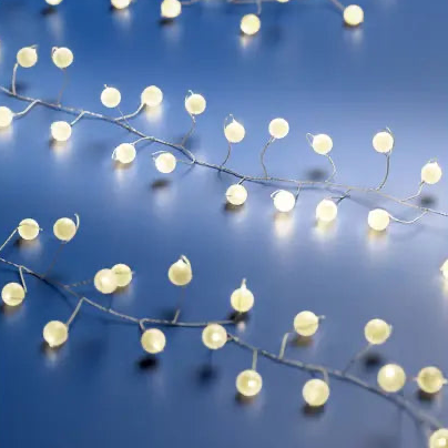 Warm white LED string lights on thin wire, draped diagonally across a dark blue reflective surface.