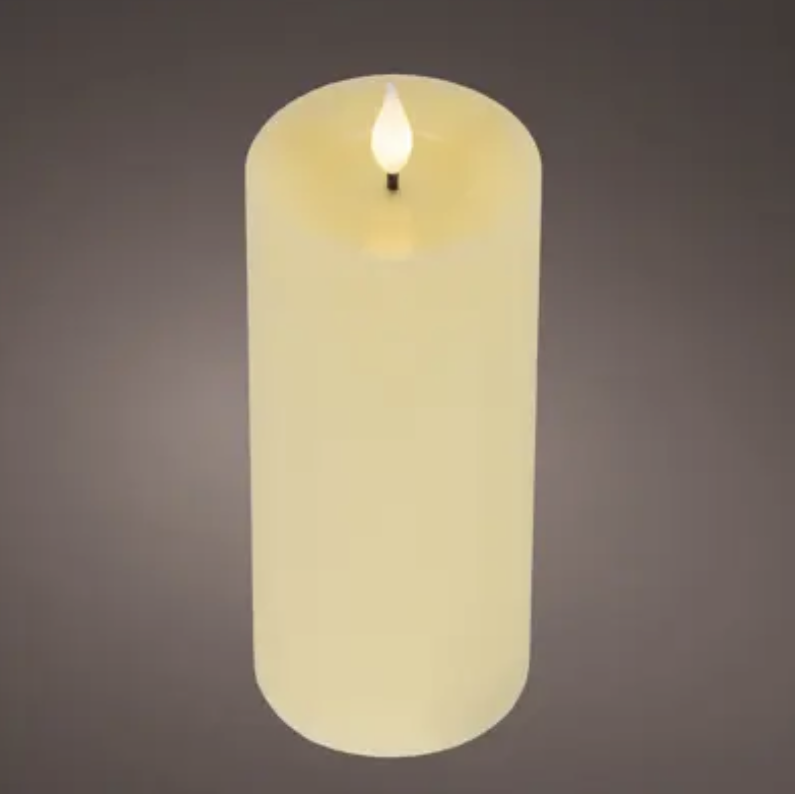 A single lit faux pillar candle in a warm cream or ivory tone, shown upright against a dark gray gradient background.