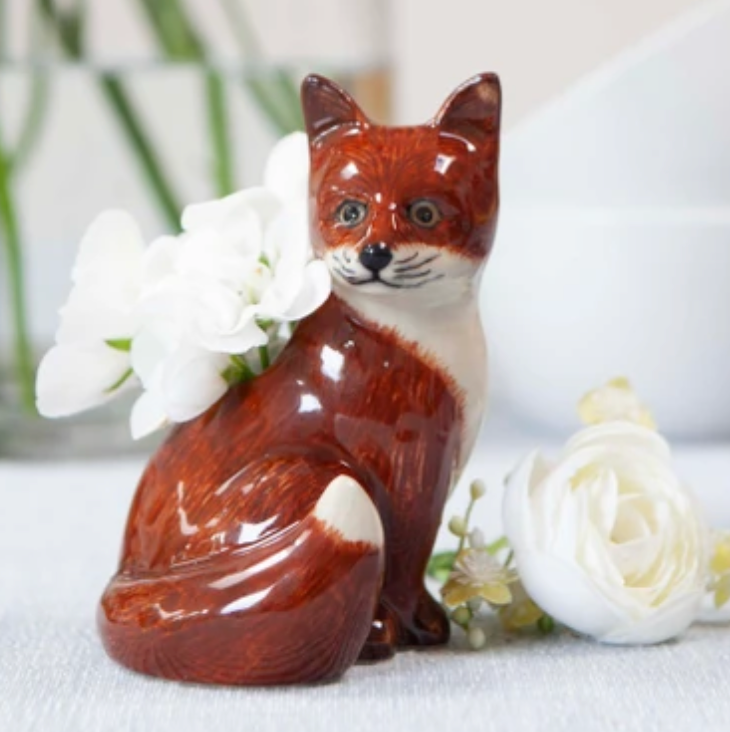 Ceramic fox figurine with white flowers on a light surface