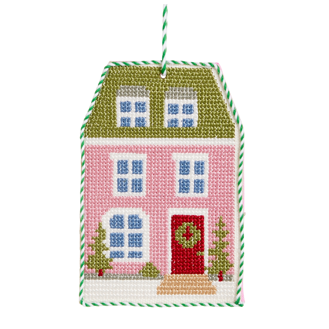 A house-shaped needlepoint ornament featuring a pink facade, green roof, red front door with a green wreath, blue windows, and small green trees, with a green-and-white striped hanging loop.
