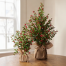 Two artificial berry garlands wrapped in burlap and tied with twine, displayed on a wooden table against a neutral indoor background.