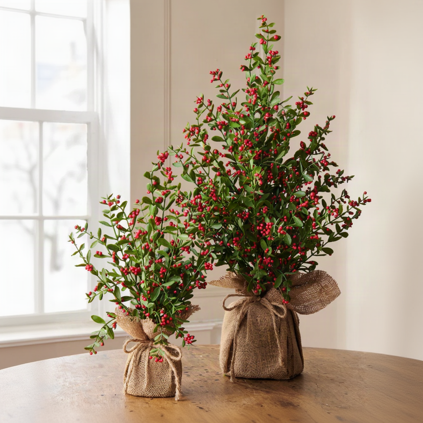 Two artificial berry garlands wrapped in burlap and tied with twine, displayed on a wooden table against a neutral indoor background.