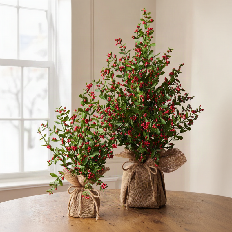 Two artificial berry garlands wrapped in burlap and tied with twine, displayed on a wooden table against a neutral indoor background.