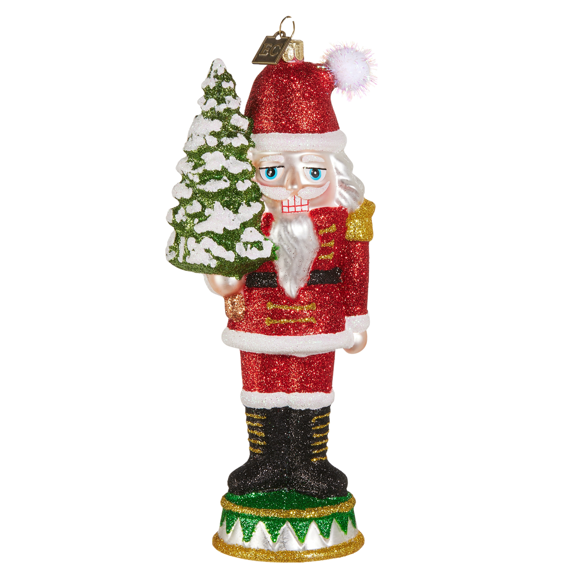 A glittery nutcracker Christmas ornament featuring a Santa-like figure in a red suit holding a small snowy tree, shown on a plain white background.